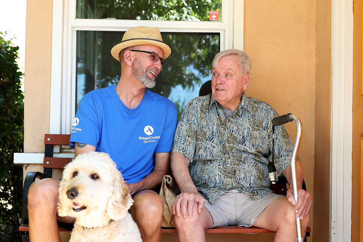 two men sitting on the pouch with a dog